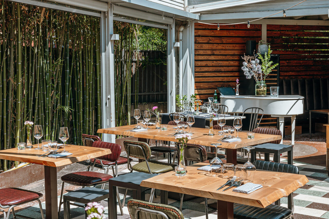 ZeroZero100 San Lorenzo Roma - Prospettiva dei tavoli all'aperto del ristorante elegante dal design ricercato e raffinato.